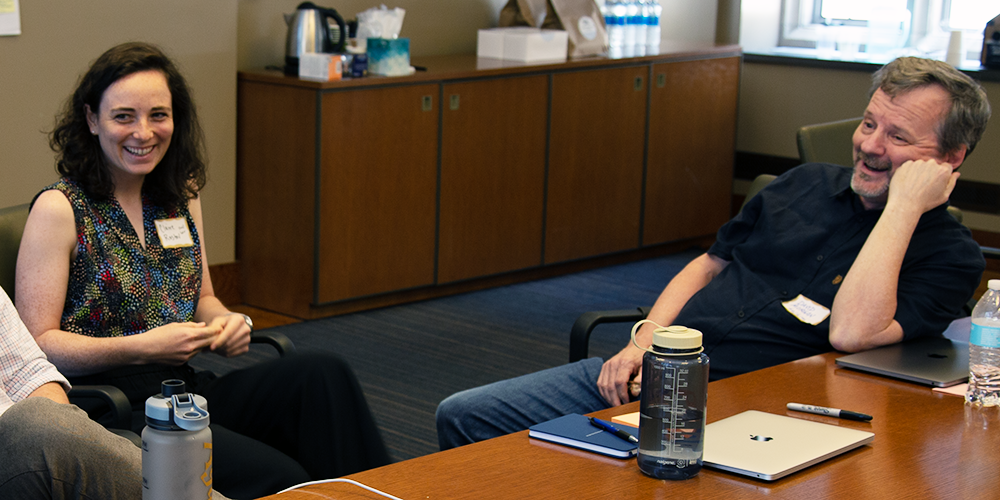 A graduate student and faculty member discuss their Duke summer course while seated at a table.